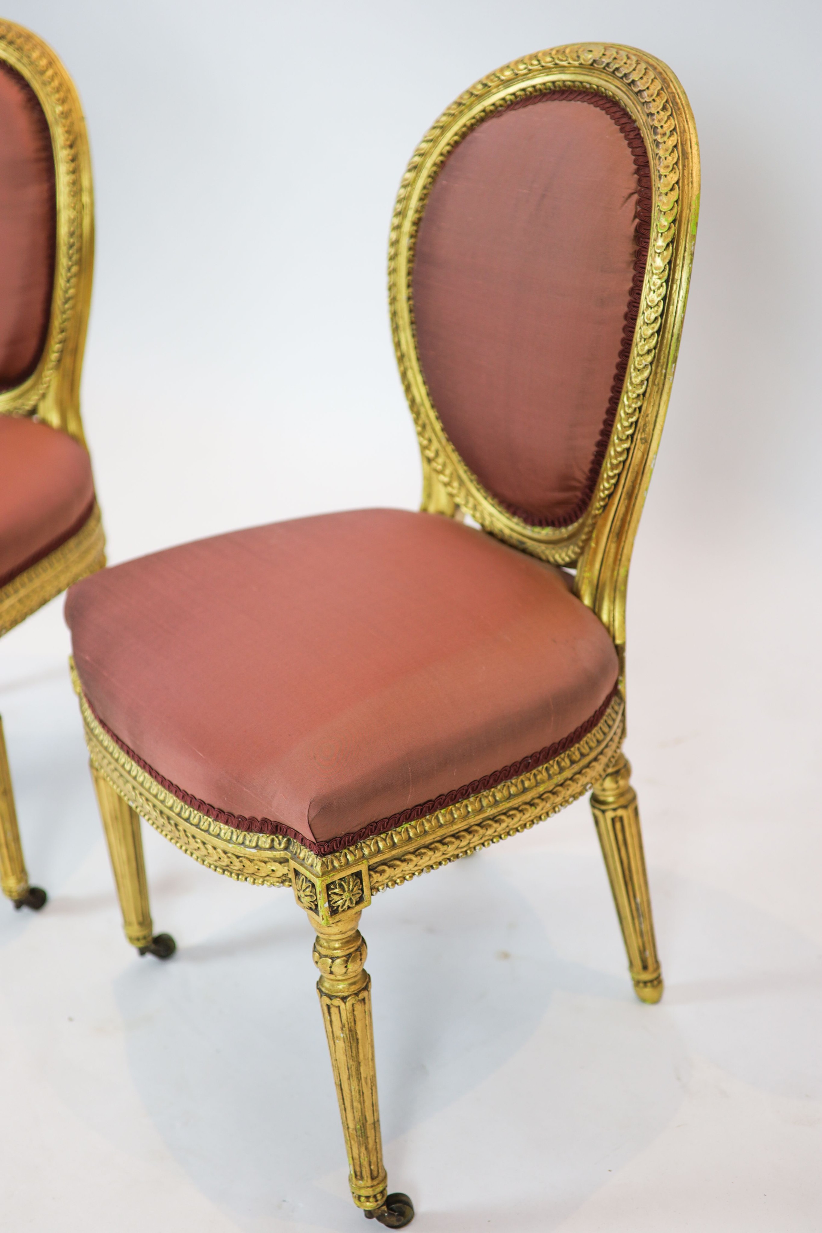 A pair of 19th century Louis XV style giltwood framed side chairs, with oval carved backs, on turned and fluted legs